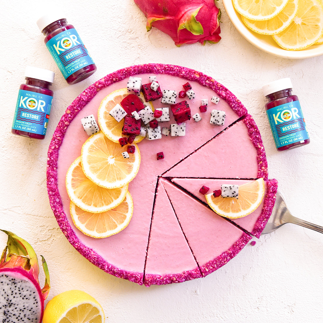 pink lemon tart with dragon fruit pieces and RESTORE on a white table